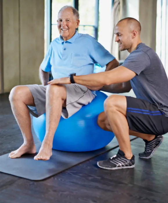 Physiotherapist, support and senior man with ball, training and elderly help for care. Men, gym and exercise for health, wellness and coaching with osteoporosis for mature rehab and wellbeing
